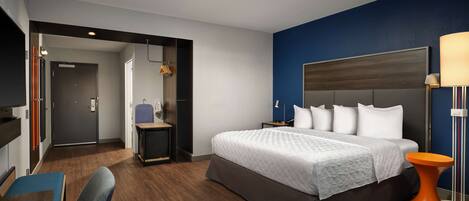 A modern hotel room with a large bed, a desk, and a chair.
