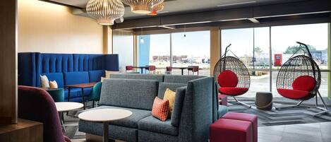 A modern lounge area with a blue sofa, grey armchairs, and a hanging chair.
