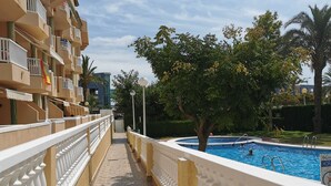 Ein Poolbereich mit gefliestem Weg, einem Pool und einem Gebäude mit Balkonen.