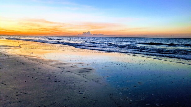 A beach with wet sand and gentle waves.