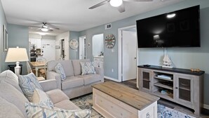 A living room with a sofa, coffee table, TV, and ceiling fan.
