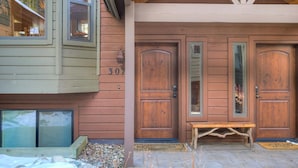 Une maison en bois avec deux grandes portes, un banc et le numéro « 307 » peint sur le mur.
