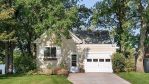 A single-story house with a garage, surrounded by trees and a well-maintained lawn. - Lake home, across the street from a golf course & minutes to shopping and more! (Sauk Centre)
