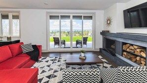 Een moderne woonkamer met een rode bank, een rug met patroon en een open haard.