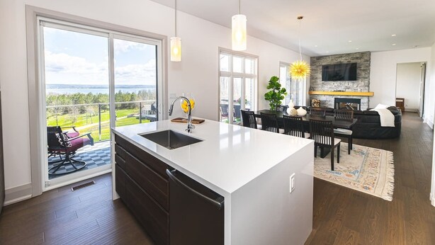 Een moderne keuken met een groot schiereiland, een eethoek met uitzicht, en een woonkamer met open haard.
