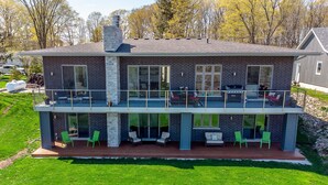 Een woonhuis met twee verdiepingen, een balkon, grote ramen en een terras.