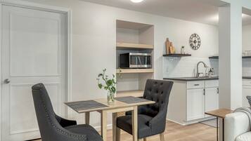A compact kitchen with a microwave, sink, and a clock on the wall.
