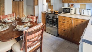 Une cuisine compacte avec des meubles de rangement en bois, un four encastré, un four à micro-ondes et un grille-pain.