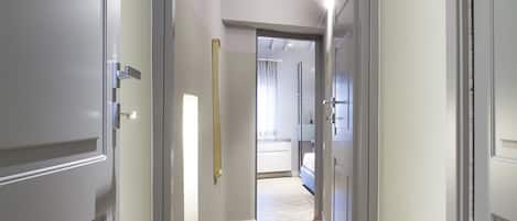 A hallway with a herringbone floor pattern, grey walls, and a wooden ceiling beam.