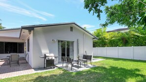 Et moderne hus med en terrasse, udendørs møbler og en grill.
