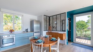 Une cuisine moderne avec un coin repas, de grandes fenêtres et une vue sur l’extérieur.