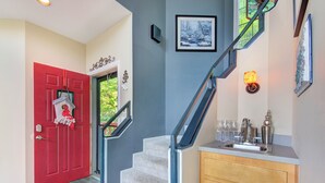 A staircase with a red door and a wooden cabinet with a sink. - Birdsong by Jackson Mountain Rentals (Gatlinburg)