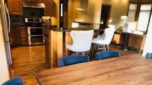 Una cocina moderna con armarios de madera, electrodomésticos de acero inoxidable y una isla central con taburetes de bar.