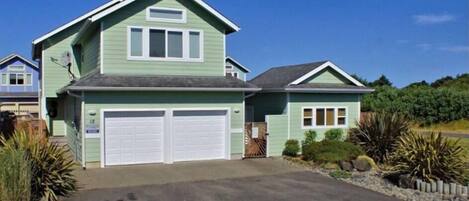 Une maison à deux étages avec un garage, une allée couverte et une pelouse bien entretenue.