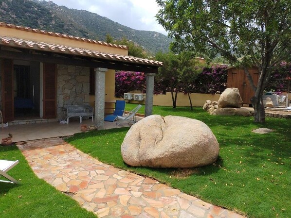 A stone pathway leading to a covered outdoor seating area with a stone building in the background.