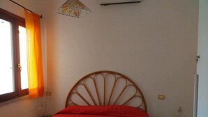 Ein Schlafzimmer mit Bett, Fenster mit Vorhängen, Klimaanlage und Nachttisch.