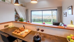 A modern kitchen with a large window, a wooden countertop, and a view of the countryside.
