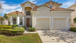 A two-story house with a garage, a covered front porch, and a well-maintained lawn. - 😎RELAX at Windsor Hills🌴, minutes to Disney - 5 bed / 5 bath, Private Pool🌞 (Kissimmee)