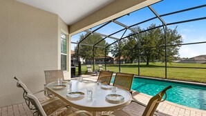 A covered patio with a pool, outdoor furniture, and a view of the surrounding area. - 😎RELAX at Windsor Hills🌴, minutes to Disney - 5 bed / 5 bath, Private Pool🌞 (Kissimmee)