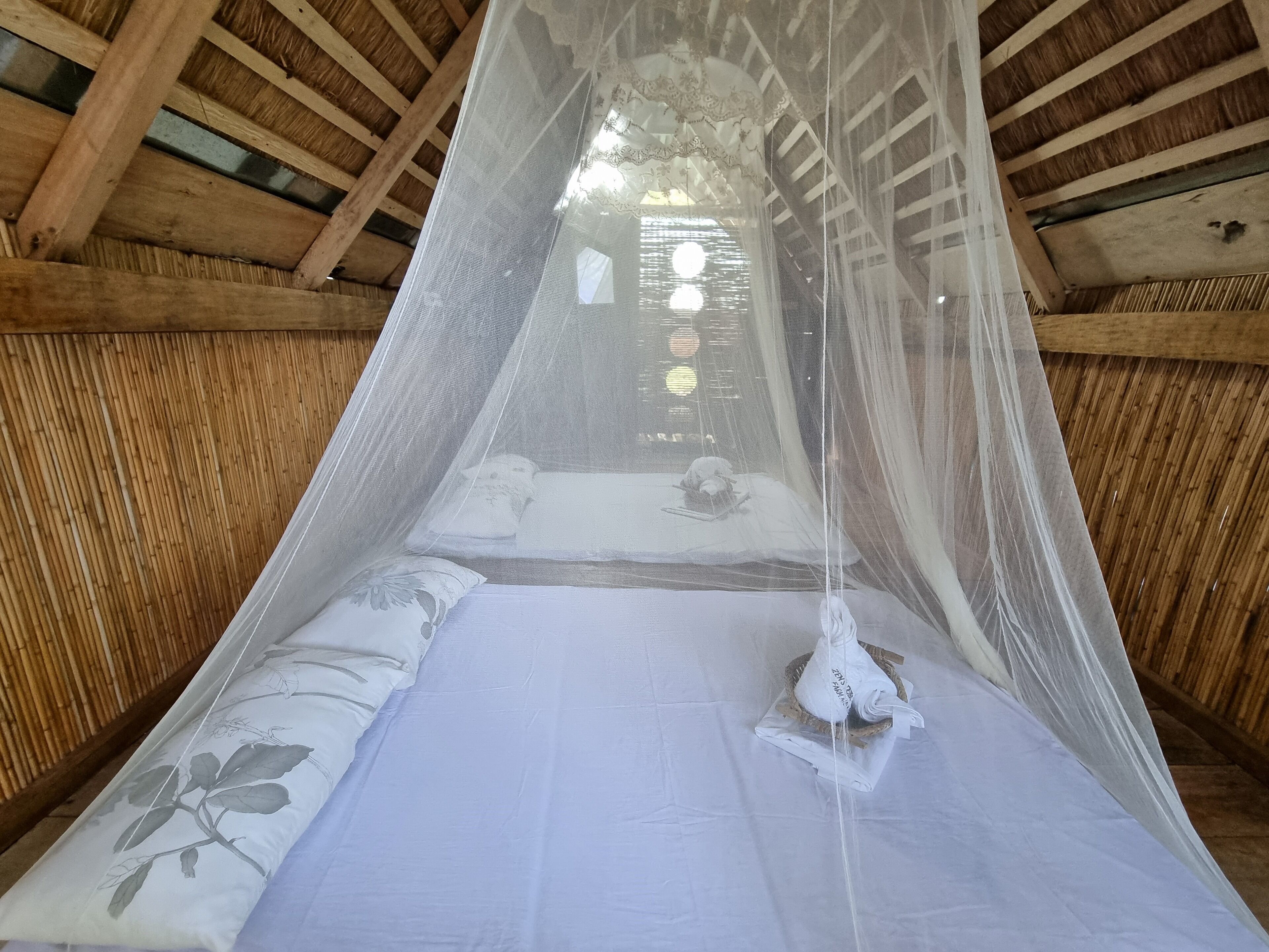 A bed with a canopy, wooden beams, and a view of the outside through the window.