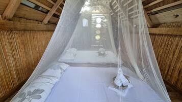 A bed with a canopy, wooden beams, and a view of the outside through the window.