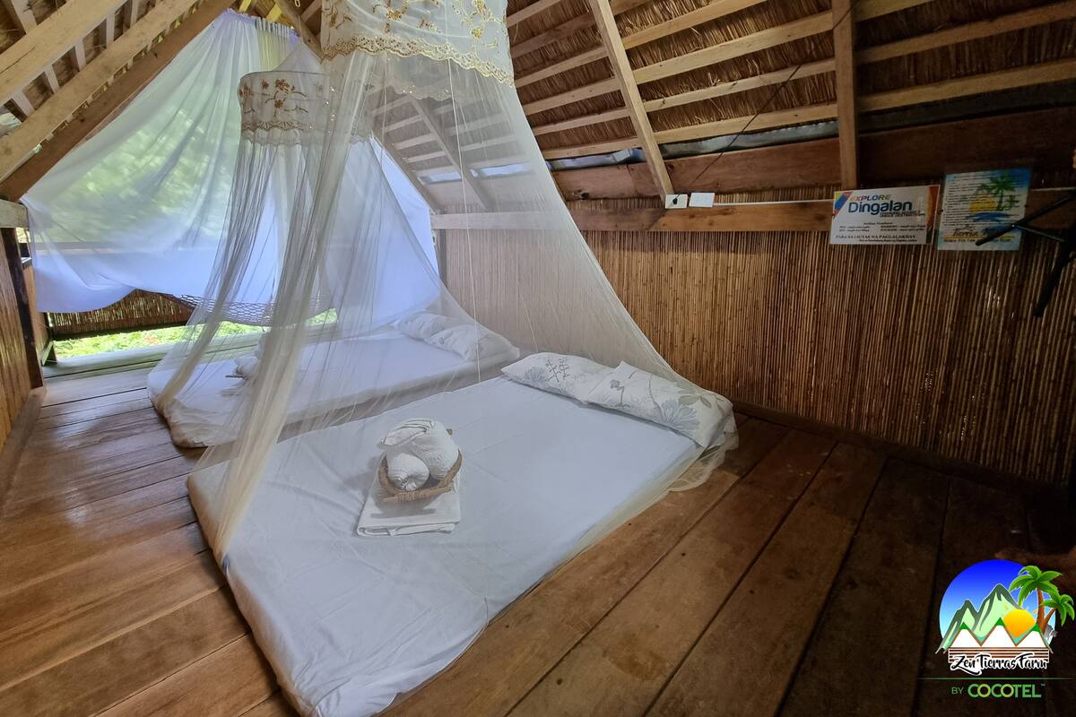 Une cabane en bois avec un lit recouvert d’une moustiquaire, une petite table avec une serviette et un plafond en bois.