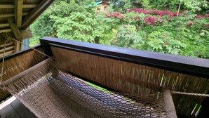A hammock under a wooden structure with a view of lush greenery and pink flowers. - Zen Tierras Farm powered by Cocotel (Dingalan)