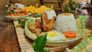A wooden interior with a dining table set with various dishes, including rice, eggs, and grilled meat. - Zen Tierras Farm powered by Cocotel (Dingalan)