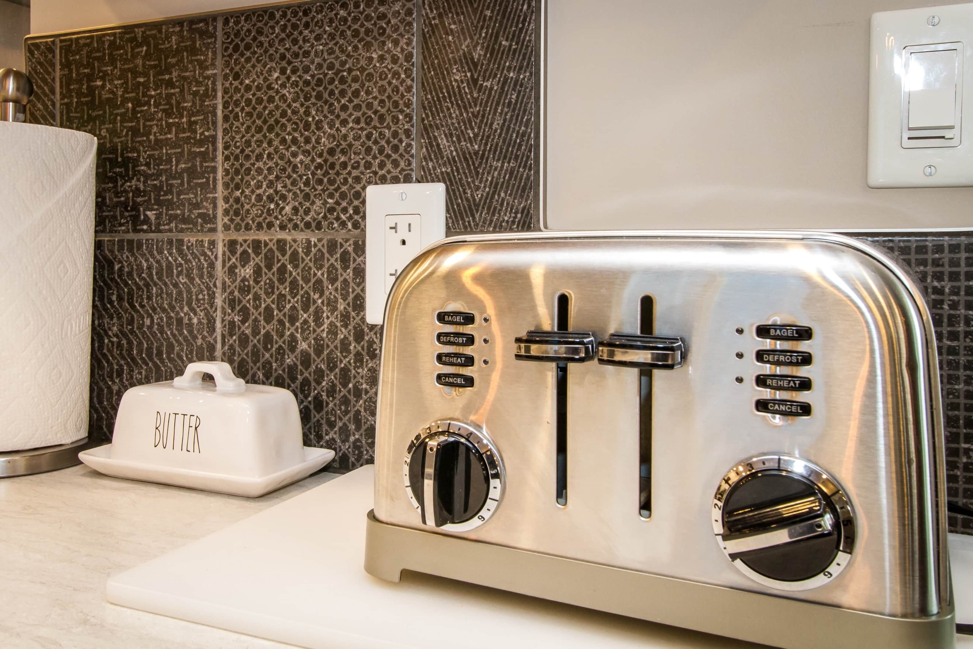 Ein Edelstahltoaster mit einem Butterbehälter auf einer Küchenarbeitsplatte.