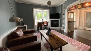 A living room with a fireplace, a TV, and a dining area with chairs and a table.