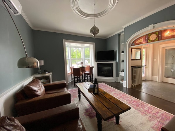 A living room with a fireplace, a TV, and a dining area with chairs and a table.