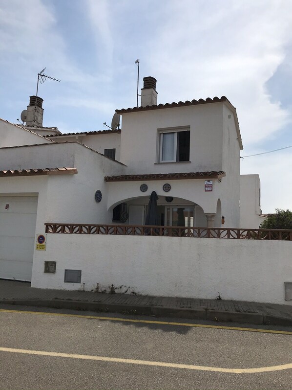 Un edificio de dos pisos con fachada blanca, un pequeño balcón y una chimenea.