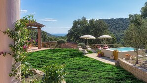 Un jardín cuidado con piscina, mobiliario exterior y una pérgola.