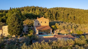 Une villa en pierre dotée d’une piscine, entourée d’une forêt dense et de collines.