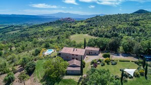 Une villa en pierre dotée d’une piscine, entourée d’une végétation luxuriante et de collines.