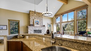 A kitchen with granite countertops, a stone backsplash, a built-in stove, and large windows offering a view of the outdoors. - Spacious Mountain Retreat w/ Amazing Views! By Gorecreek Rentals (Avon)