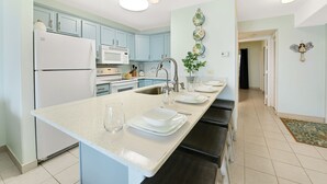 Uma cozinha moderna com ilha central, eletrodomésticos brancos e armários azul claro.