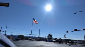 A street intersection with traffic lights, vehicles, and an American flag. - Small house (Los cerillos)