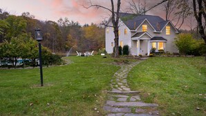 A house with a stone pathway leading to the front door, surrounded by a grassy lawn and trees.