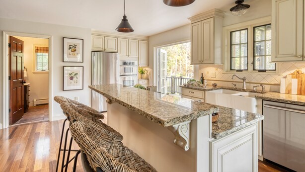 A spacious kitchen with white cabinetry, a granite countertop, and pendant lighting.