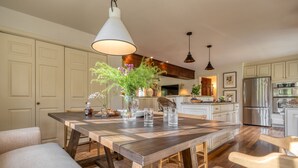 A spacious kitchen with a large wooden table, white cabinets, and stainless steel appliances.