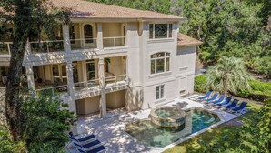 A two-story house with a swimming pool, sun loungers, and a lush garden. - 8 bedroom/7 bathroom 3rd row corner home, luxurious and family friendly (Hilton Head Island)