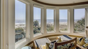 Habitación con amplios ventanales que dan a una playa, techo curvo y vista al océano.