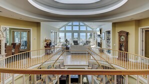 Un interior espacioso con una escalera central, ventanas amplias y vistas al exterior.
