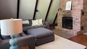 A living room with a sofa, ottoman, and a fireplace.