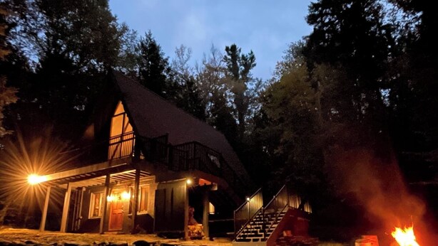 A lodge with a large fireplace, a covered porch, and a staircase leading to the upper level.
