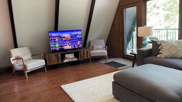 A modern living room with a television, two chairs, a sofa, and a large window.