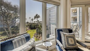 A room with large windows, a view of a building, and a small table. - 2 bedroom villa with oceanfront views from your balcony located in Windsor Ct (Hilton Head Island)