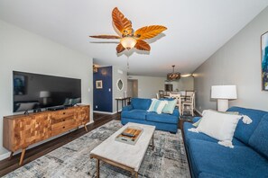 Relax in this stylish living room with a flat-screen TV, plush sofa, and dining area.