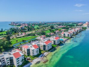 Un hôtel en bord de mer composé de plusieurs bâtiments, chacun doté de balcons et d’un toit rouge. L’établissement comprend une plage privée et est entouré de verdure ainsi que d’un parcours de golf.
